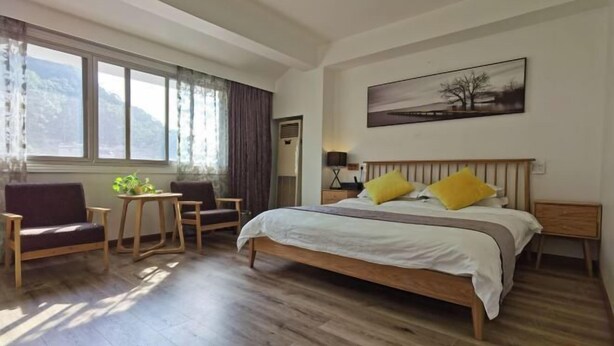 A bedroom with a bed, a chair, a small table, and a window with curtains. - Ruyilou Hostel (Yueqing)