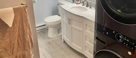 A bathroom with a toilet, sink, and a washing machine.