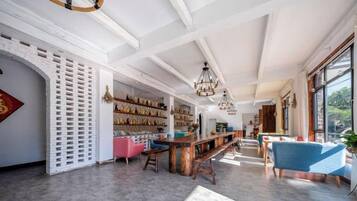 A spacious interior with a high ceiling, a long wooden bar, and seating areas.