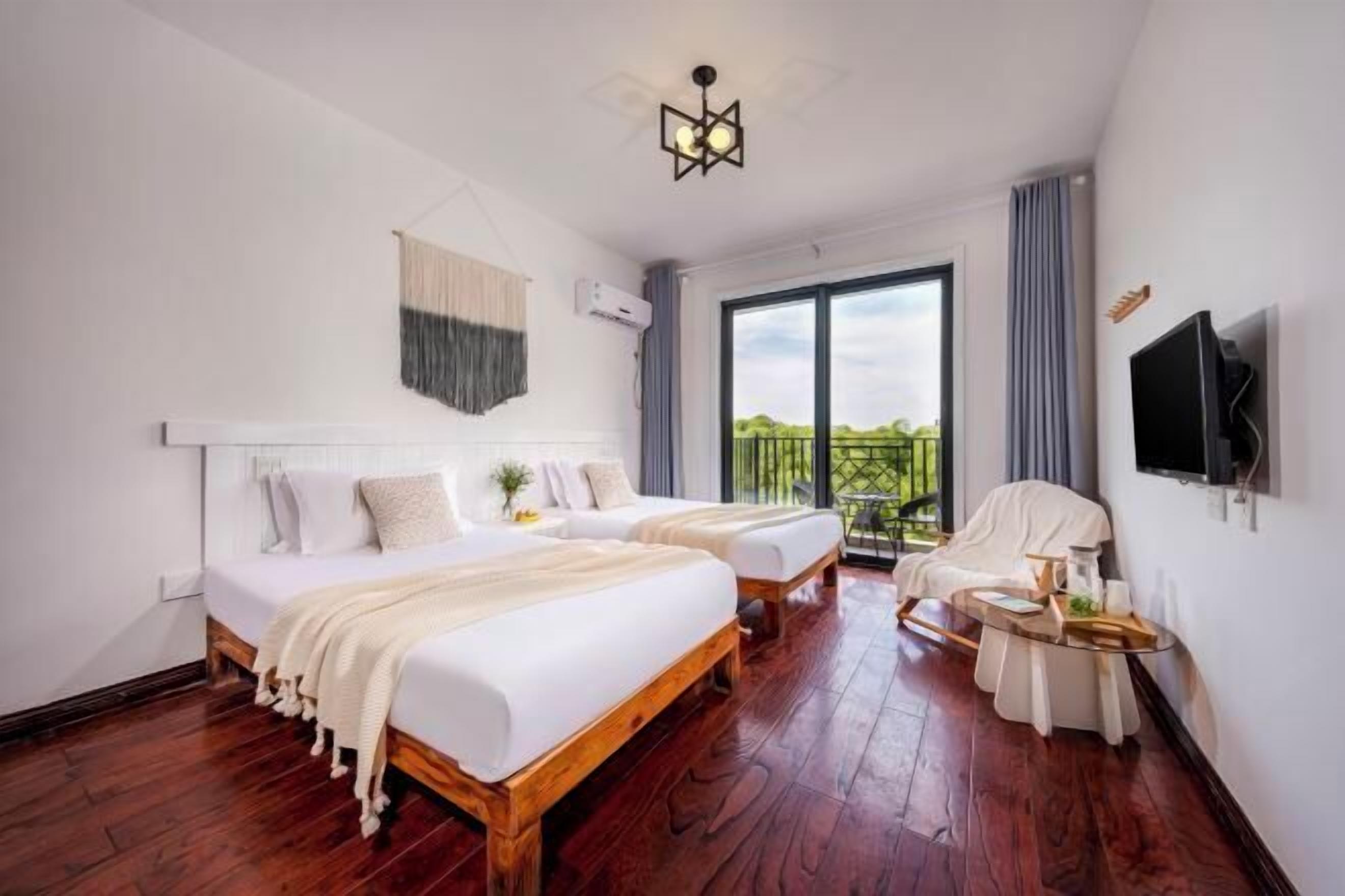 A hotel room with two beds, a TV, a balcony, and a wooden floor.