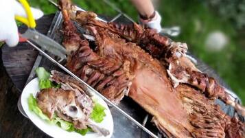 A roasted whole animal on a grill with a plate of greens beside it.