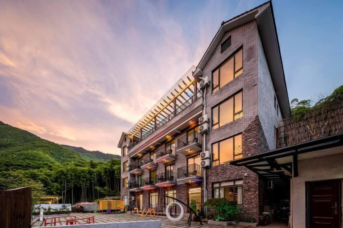 Un hotel de diversos pisos amb balcons, una zona de piscina i un paisatge de muntanyes al fons.