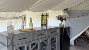 A tented accommodation with a grey cabinet, a bottle, and a small table. - Heritage Ranch 'Gallatin' Glamping Tent (10) (Bozeman)