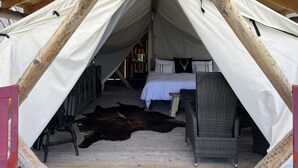 A tented accommodation with a bed, a wicker chair, and a large fur rug. - Heritage Ranch 'Gallatin' Glamping Tent (10) (Bozeman)