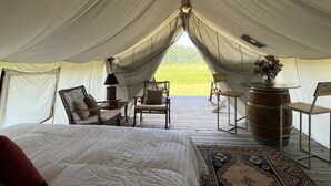 A tent with a bed, chairs, a table, and a rug. - Heritage Ranch 'Rainbow' Glamping Tent (12) (Bozeman)