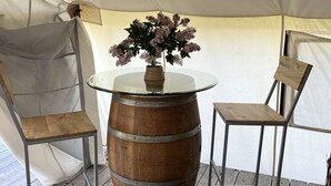 A tent with a round table, two chairs, and a decorative vase with flowers. - Heritage Ranch 'Rainbow' Glamping Tent (12) (Bozeman)