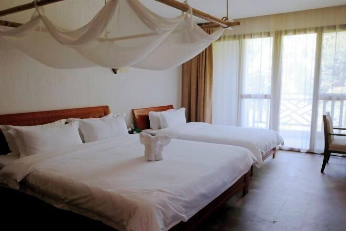 A hotel room with two beds, a canopy bed, and a balcony with curtains.