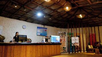 A reception area with a wooden counter, a computer, and a wall clock.