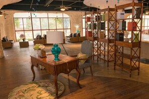 Una habitación amplia con suelo de madera, una mesa redonda con un jarrón, una silla y una estantería.