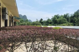 Un edificio con varias unidades de aire acondicionado, un jardín ajardinado con diversas plantas y vistas a un paisaje montañoso.