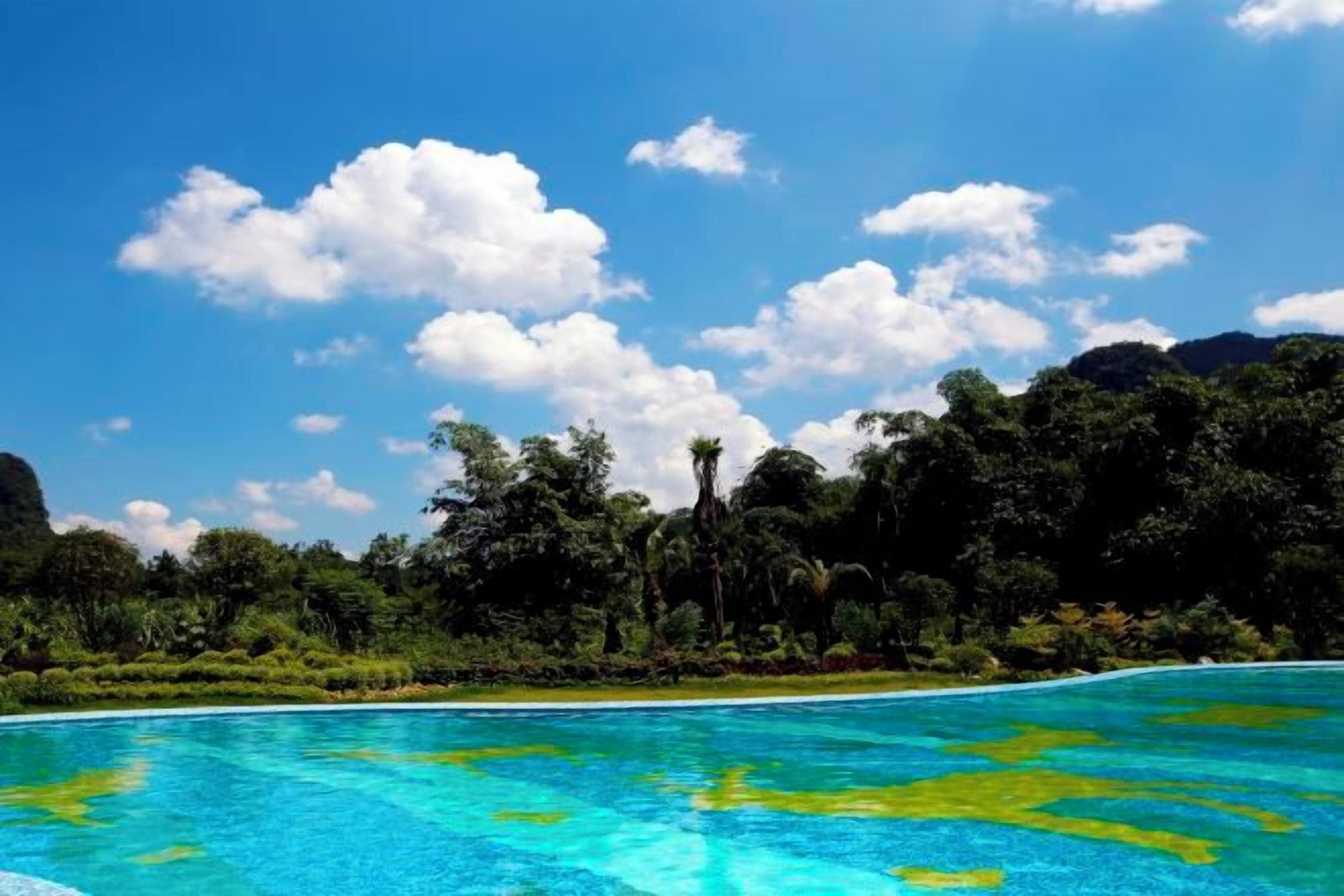 Uma praia tropical com águas azul-claras, vegetação exuberante e montanhas ao fundo.