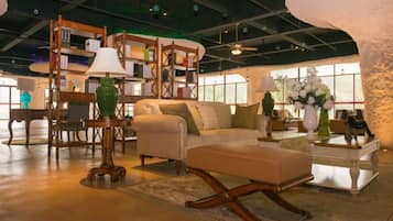 A spacious room with a large sofa, a coffee table, and a bookshelf.