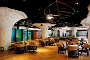 A restaurant with round tables and chairs, a bar area, and a ceiling with geometric light fixtures. - Luminggu Hotel (Luzhai)