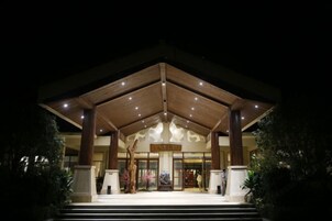 Entrada de hotel con fachada de madera, grandes columnas y un cartel sobre las puertas.