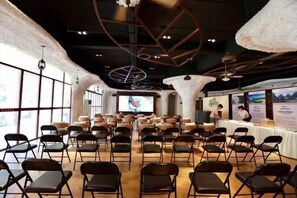 A conference room with rows of chairs, a large screen, and a stage area. - Luminggu Hotel (Luzhai)