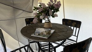 A round table with four chairs, a magazine, and a vase with flowers. - Heritage Ranch 'Big Sky' Glamping Tent (11) (Bozeman)