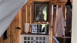 A wooden cabin interior with a television, a cabinet with glass doors, a sink, and a white curtain. - Heritage Ranch 'Big Sky' Glamping Tent (11) (Bozeman)
