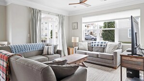 A living room with two sofas, a coffee table, a TV, and a ceiling fan. - Grande Getaway Walking Distance to the Beach (Rehoboth Beach)