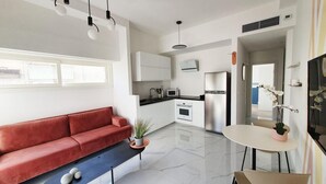 Una cocina moderna con armarios blancos, un refrigerador de acero inoxidable y una encimera negra.
