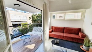 A modern apartment with a red sofa, a small table, and a potted plant. - Yosef Terracotta in Tel Aviv-yafo (Tel Aviv)