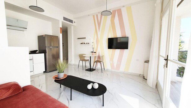 A modern kitchen with a built-in refrigerator, a dining area with a black table and chairs, and a TV mounted on the wall. - Yosef Terracotta in Tel Aviv-yafo (Tel Aviv)