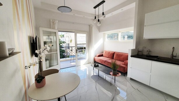 Una sala de estar moderna con un sofá, una mesa de comedor y una zona de cocina con un fregadero y armarios.