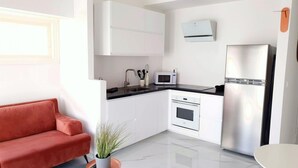Una cocina moderna con armarios blancos, un refrigerador de acero inoxidable, un microondas y un fregadero.