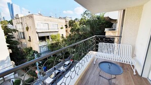 A balcony with a white metal railing, a white bench, and a small round table. - Yosef Terracotta in Tel Aviv-yafo (Tel Aviv)