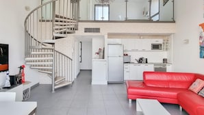 A modern apartment with a living room, kitchen, and a spiral staircase.