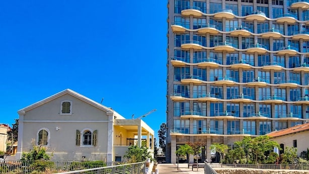 A modern building with multiple balconies and a construction crane nearby.