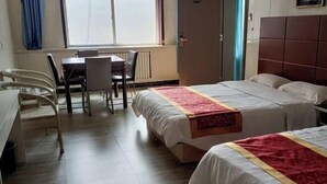 A hotel room with two beds, a dining table with chairs, a window with curtains, and a radiator. - Jinhaiwan Homestay (Jixian Passenger Station) (Ji County)