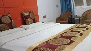 A hotel room with a bed, a headboard, two pillows, a table with chairs, and a window with curtains. - Jinhaiwan Homestay (Jixian Passenger Station) (Ji County)