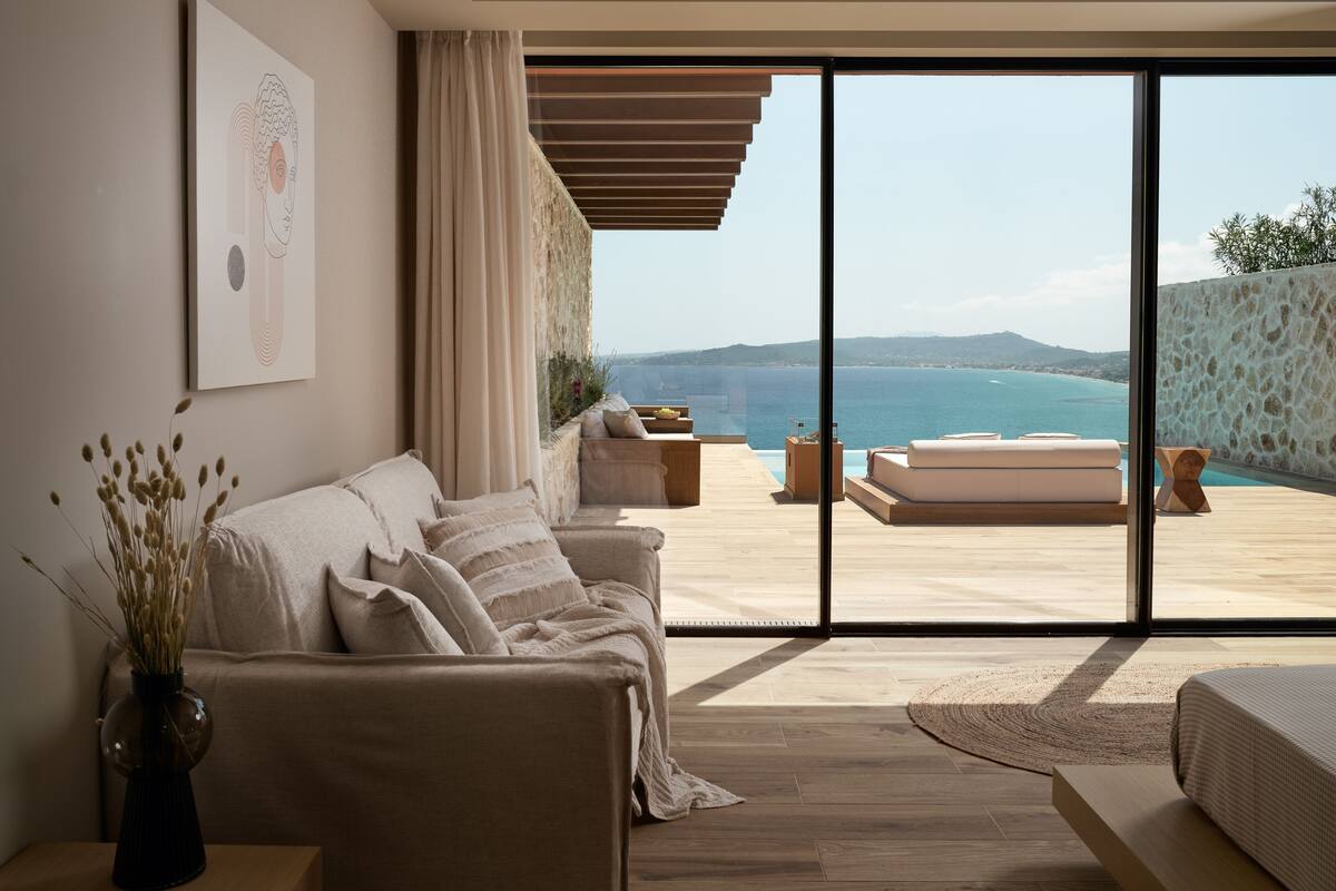 A modern living room with a sofa, a coffee table, and a view of the sea.