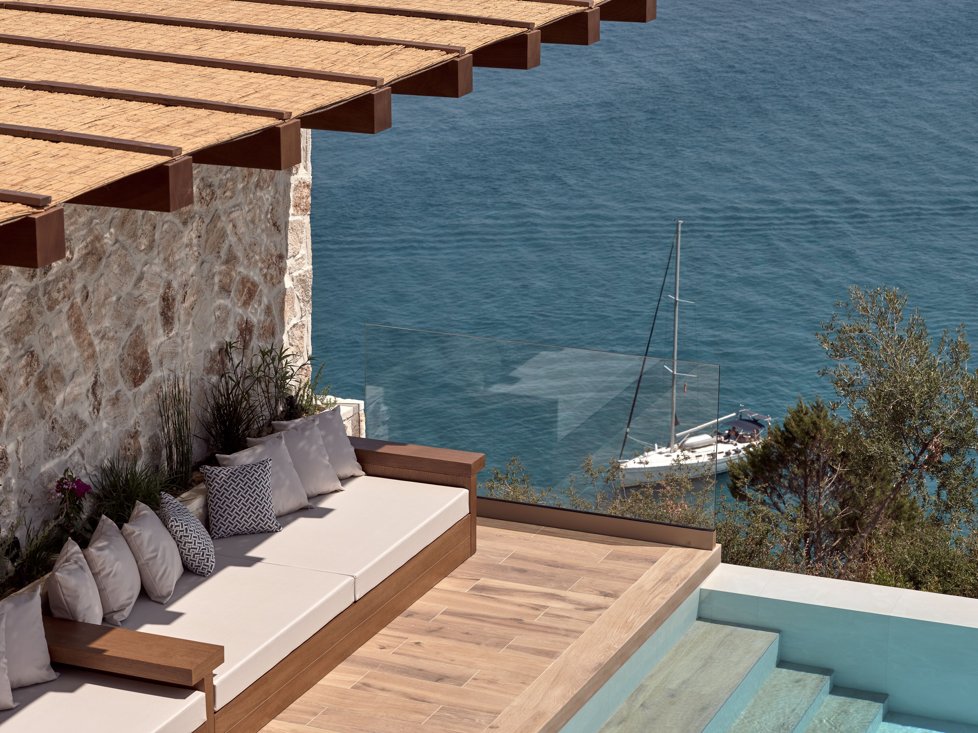 A balcony with a stone wall, a wooden deck, and a view of the sea.
