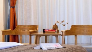 Une pièce avec deux chaises en bois, une petite table et un lit avec une couverture.