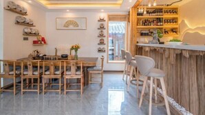 Un espace repas moderne, avec des meubles en bois, un bar orné de bouteilles de vin et des éléments décoratifs sur les murs.