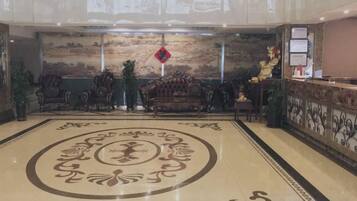 A lobby with a reception desk, ornate sofas, and a decorative floor pattern.