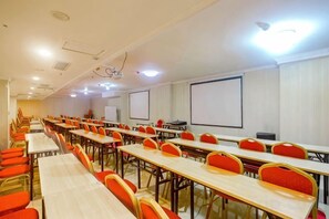 A conference room with multiple tables and chairs, a projector screen, and a whiteboard. - Shuangsheng Saifu Business Hotel (Harbin)