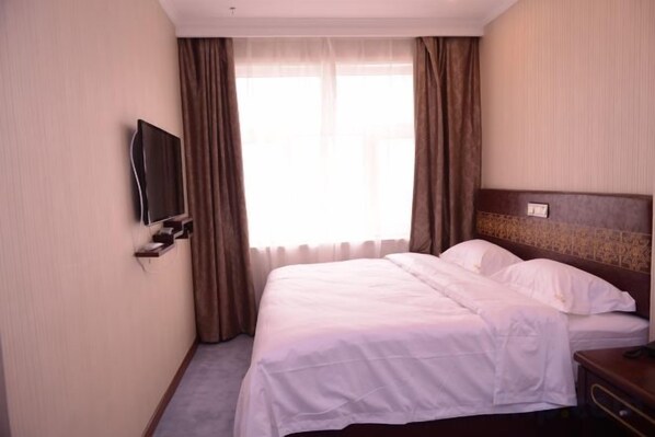 A hotel room with a bed, a television mounted on the wall, and a window with curtains. - Shuangsheng Saifu Business Hotel (Harbin)