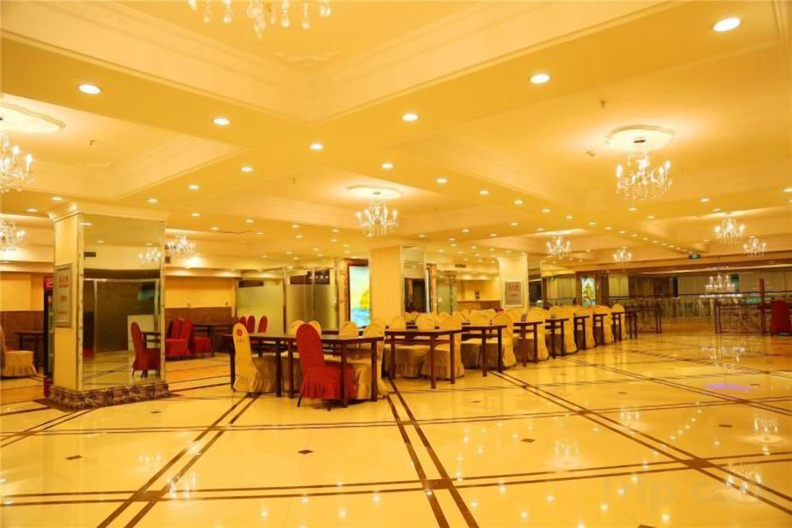 A spacious hotel lobby with a polished floor, multiple seating areas, and a chandelier.