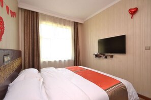 Ein Hotelzimmer mit einem Bett, einem an der Wand montierten Fernseher und einem Fenster mit Vorhängen.