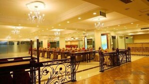 A spacious lobby with a high ceiling, chandeliers, and a seating area with tables and chairs.