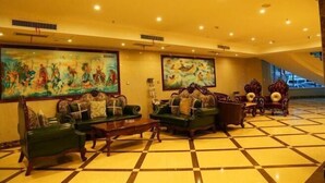 A lobby with green sofas, a checkered floor, and large paintings on the walls.