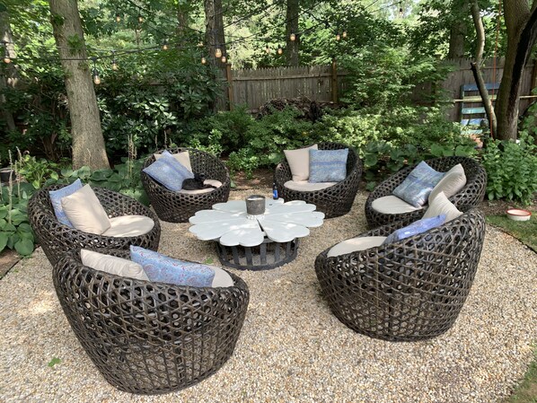 A garden seating area with wicker furniture and a central table.