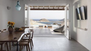 Ein moderner Essbereich mit Blick auf das Meer und einer Steinwand.