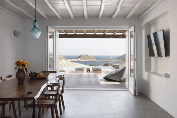A modern dining area with a view of the sea and mountains.