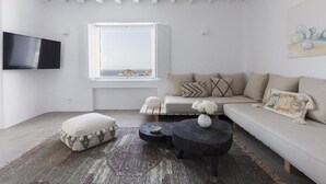 Ein modernes Wohnzimmer mit großem Fenster, Flachbildfernseher, Sofa und Couchtisch.