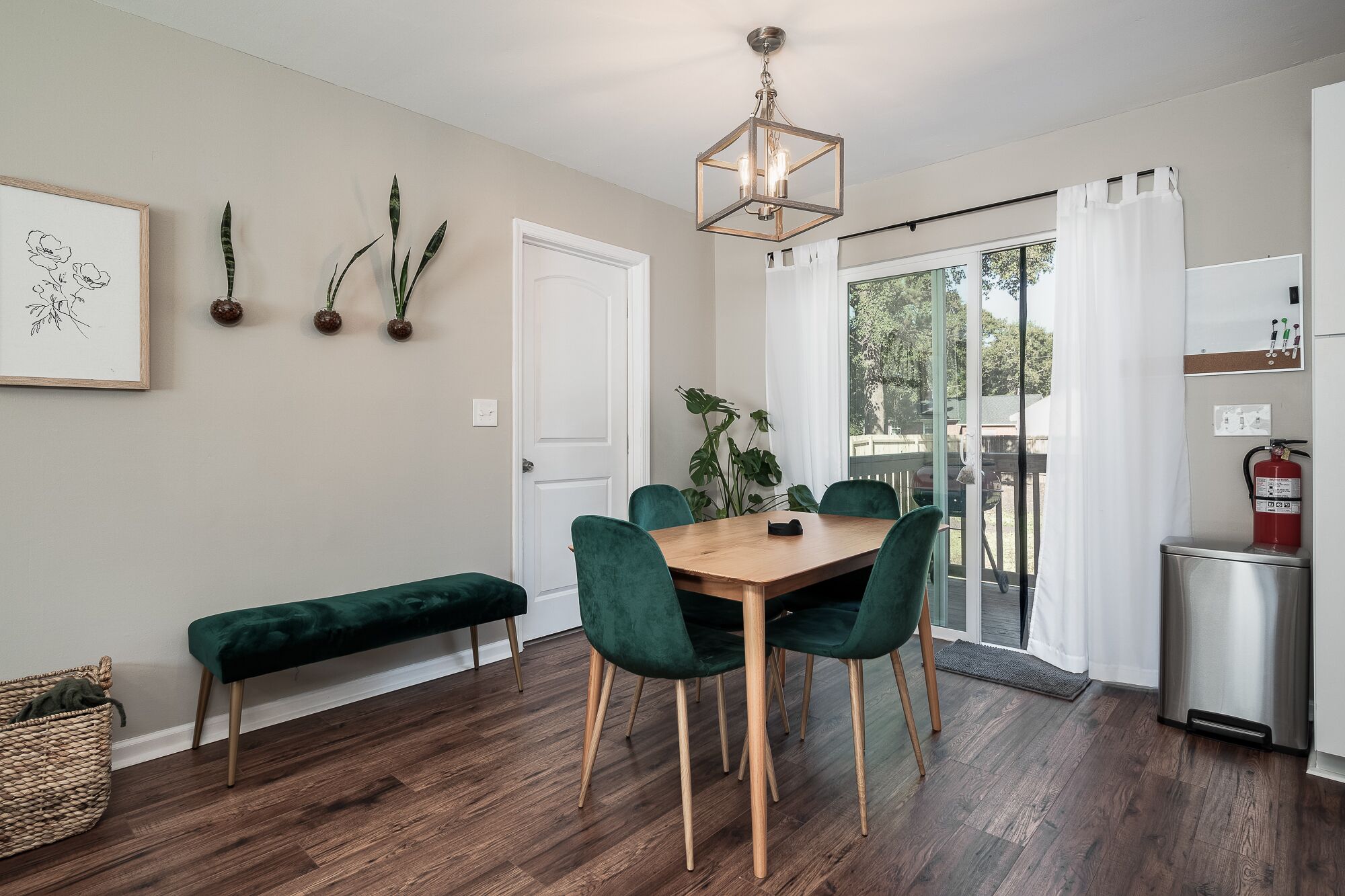 A dining area with a wooden table, green upholstered chairs, a bench, and a hanging light fixture.