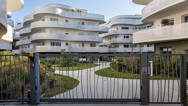 Un moderno edificio residencial con balcones curvos y una entrada portonada.