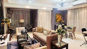 Una sala moderna con un sofá, una mesa de centro y elementos decorativos. Hay un comedor con una mesa y sillas.
